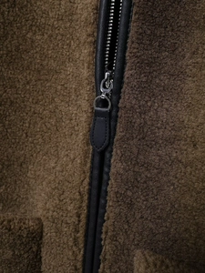Detail of metal zipper with black leather trim on a fleece sherpa jacket coat