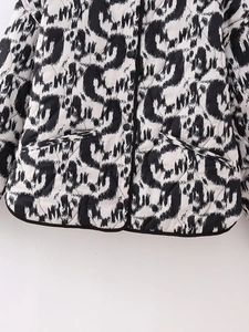 Detail of quilted jacket showing black and white animal print with diamond stitching and buttons