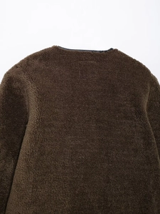 Detail of dark brown faux shearling jacket with black leather trim and soft fleece texture