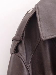 Detail view of dark brown leather biker jacket showing shoulder epaulets and metal buttons