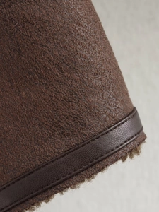 Detailed close-up of brown suede jacket with faux fur lining and leather piping trim