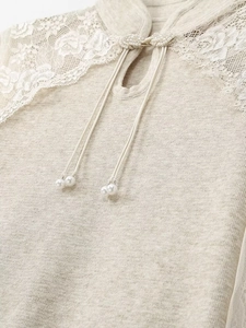 Detailed close-up of pearl bead buttons and lace stitching on beige knitwear