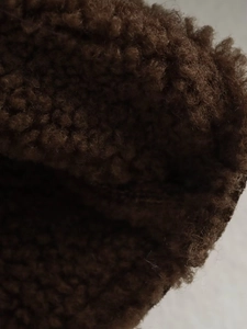 Close-up detail of plush dark brown sherpa fleece fabric showing curly texture