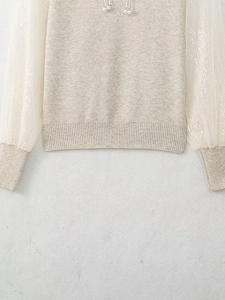 Detail of grey knit sweater with lace mesh sleeves and ribbed hem textures