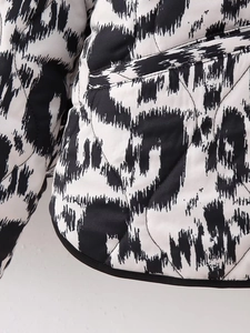 Detail of diamond quilted texture and side pocket on black and white printed jacket