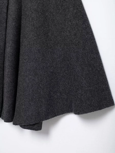 Detail shot of charcoal gray knit wool blend fabric texture on the cape coat outerwear