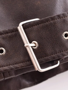 Detailed close-up of dark brown washed leather jacket with silver metal buckle and stitching