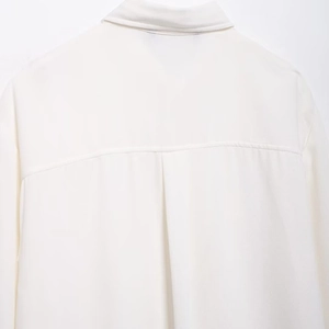 White long-sleeved crepe shirt featuring a classic collar and back inverted pleat detail