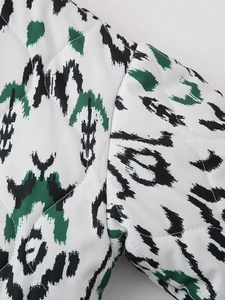 Detailed close-up showing diamond-shaped quilting and green geometric ikat print on fabric