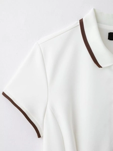 Détail du polo blanc montrant le col rayé marron et la texture des poignets côtelés