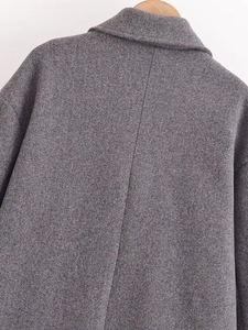 Vista dettagliata del retro di un cappotto di lana grigio che mostra la trama del tessuto