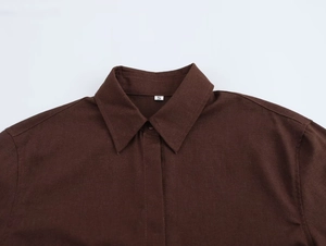Dettaglio del colletto di una camicia marrone scuro con revers a punta ed etichetta S