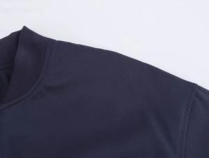 Detail of navy blue bomber jacket showing ribbed knit collar and high-quality fabric texture