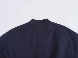 Close-up of the ribbed knit collar and shoulder detail on a navy blue bomber jacket