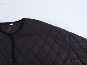 Detail of black quilted diamond jacket featuring a round neckline and front buttons