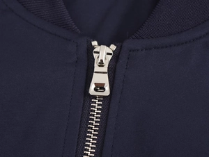 Detail of high-quality metal zipper and navy blue fabric on short fashion baseball jacket