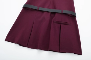Gros plan sur la robe plissée bordeaux avec une fine ceinture noire et un tissu sergé