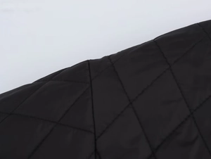 Detail of black quilted jacket featuring diamond stitching and matte fabric texture