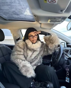 Detail of grey faux fur coat with thick collar and plush texture shown in car setting