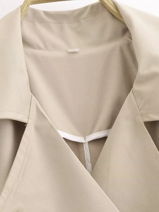 Dettaglio del risvolto del trench beige con trama in twill e cuciture interne bordate