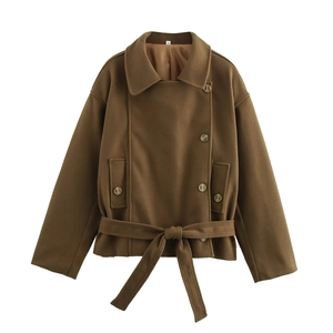 Detail of caramel wool coat showing textured fabric, metal buttons and waist tie