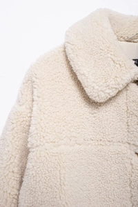 Detailed close-up of cream fleece jacket showing heavy lapel and textured shearling fabric