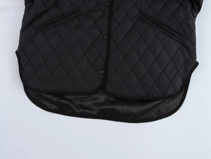 Detail of black diamond quilted jacket showing snap buttons and asymmetric curved hemline