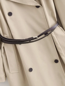 Dettaglio di un trench doppiopetto beige classico con cintura in pelle scura e revers