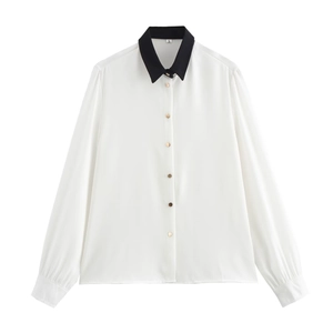 Dettaglio camicia bianca a maniche lunghe con colletto nero e bottoni dorati