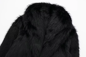 Detail shot of the long, dense black faux fur texture on the luxurious wide collar jacket