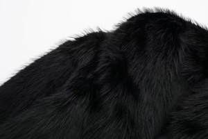 Close-up of premium black faux fur texture with dense glossy long fibers and soft feel