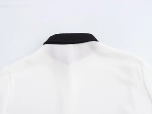 Dettaglio del colletto nero classico sulla camicia bianca a maniche lunghe da donna