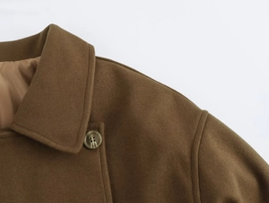 Detailed close-up of camel wool coat with marble texture buttons and fine stitching