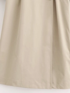Dettaglio dell'orlo del trench beige con pieghe eleganti e cuciture rifinite