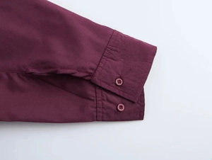 Close-up of buttoned cuffs on a burgundy raglan sleeve shirt with fine stitching