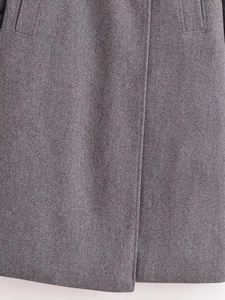 Dettaglio cappotto in lana grigia con texture del tessuto spessa e tasche verticali