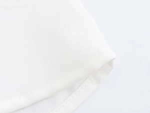 Dettaglio macro della camicia bianca a maniche lunghe con cuciture sull'orlo e tessuto
