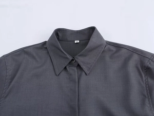 Dettaglio camicia grigio scuro con colletto classico, etichetta taglia S e trama