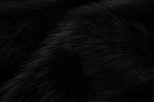 Close-up of thick black faux fur fabric with glossy texture for winter coats