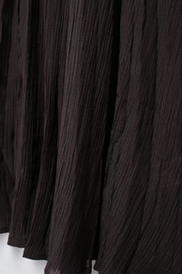 Detailed close-up showing the fine pleated texture and dark brown fabric of this knitted skirt
