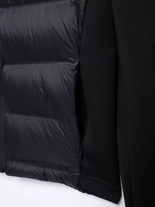 Detail of hybrid hooded puffer jacket showing quilted nylon and knit fabric with zipper