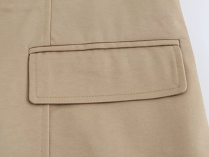 Dettaglio del gilet kaki che mostra la tasca a pattina e le cuciture di qualità