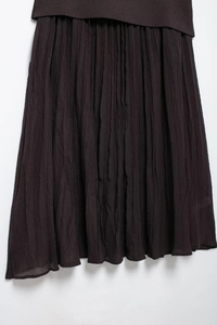 Detail view of deep coffee pleated knit midi skirt showing fine vertical texture and hemline