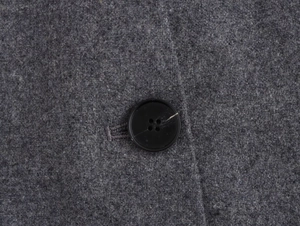 Detail shot of charcoal grey wool blend fabric texture and a black resin button on the blazer