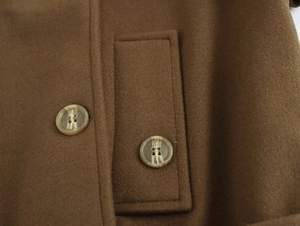 Detail of dark brown wool coat featuring marble textured buttons and premium stitching