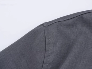 Dettaglio del tessuto twill grigio scuro che mostra cuciture fini sulla spalla della camicia