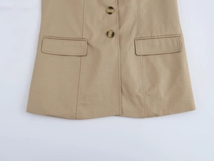 Dettaglio del gilet kaki con bottoni tartarugati e tasche con patta in tessuto pregiato