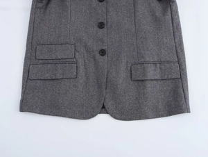 Detailed macro view of grey wool texture, black buttons, and flap pockets on a blazer