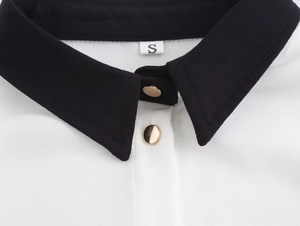 Dettaglio del colletto nero a contrasto con bottoni dorati ed etichetta taglia S su camicia
