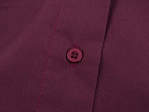 Detailed macro view of dark red shirt fabric texture and matching resin button